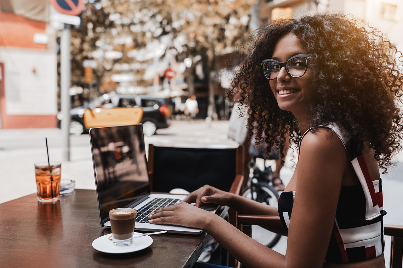 Curly-girl-in-glasses-with-netbook-in-outdoor-cafe