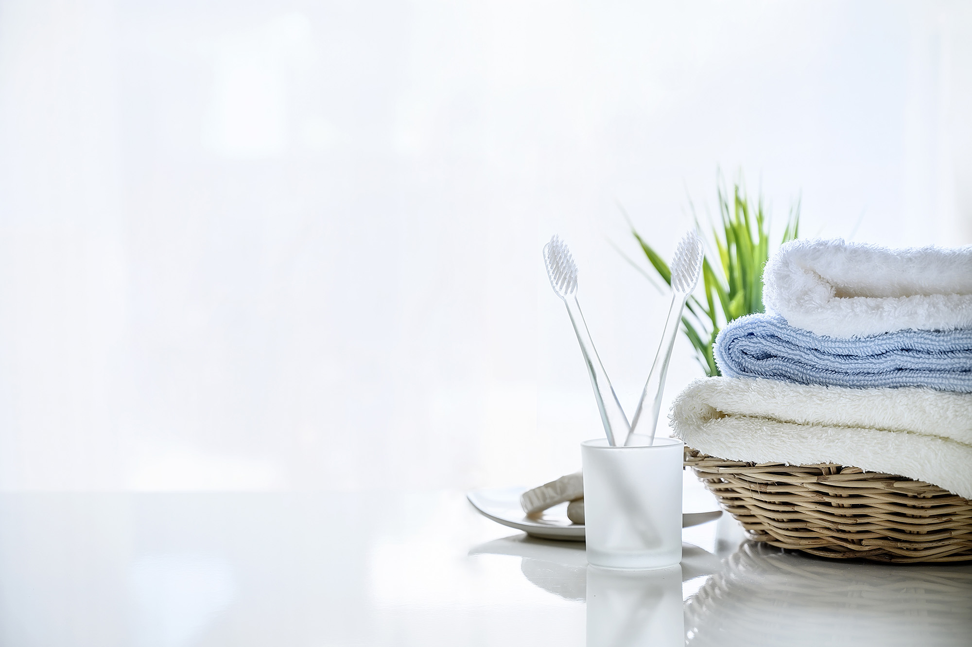 soft towels in basket and toothbrush on white background, copy space for product display.